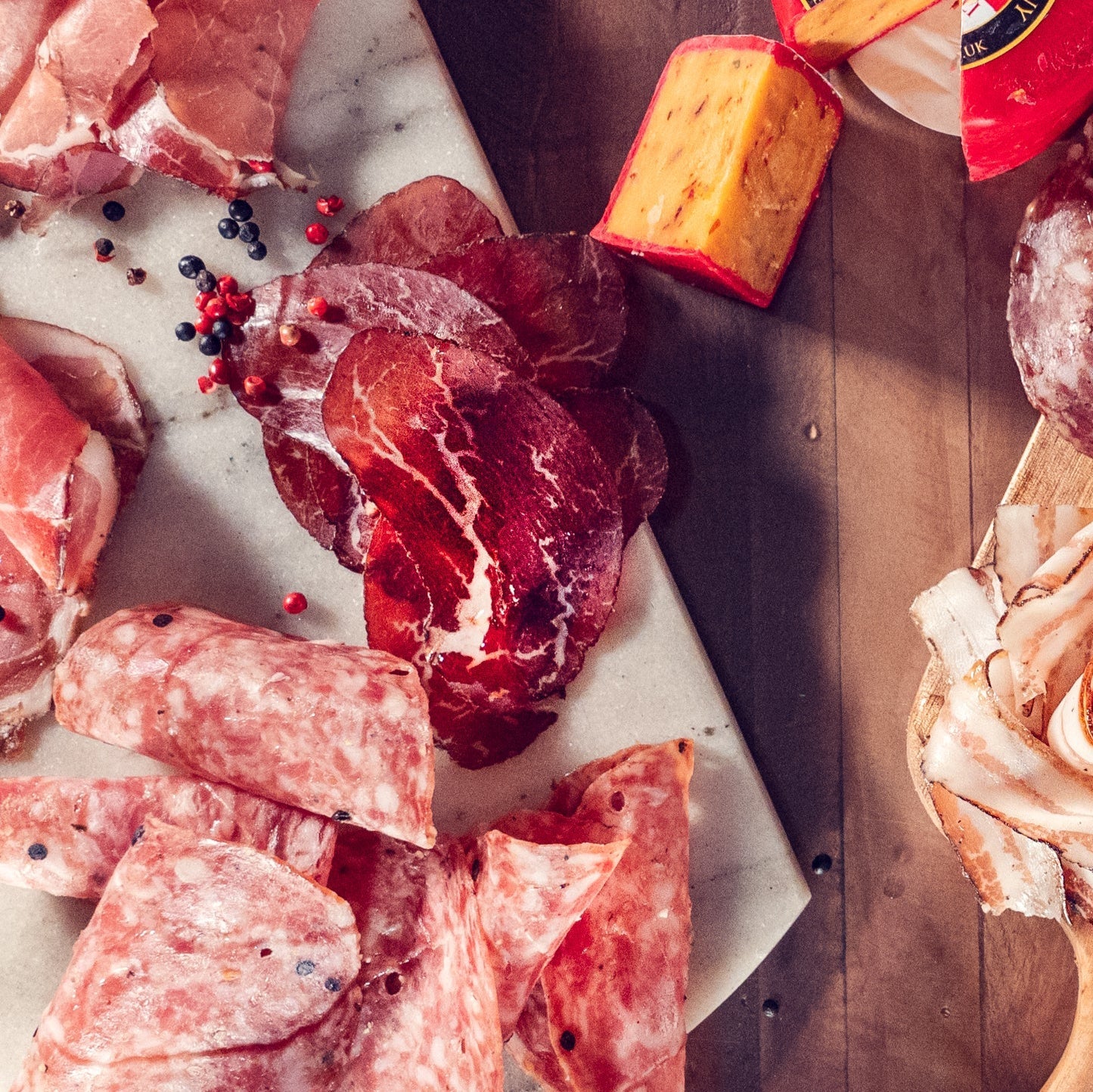 Assorted cured meats on a wooden table with a decorative scarf.